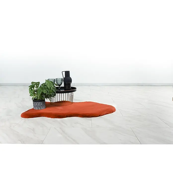 Kunstfell Happy - Terra, 90 x 60 cm, 100 % Polyester (Flor) - Eine Zimmerpflanze, zwei Gläser und eine schwarze Karaffe auf einem Tisch mit orangem Teppich auf einem hellen, gefliesten Boden.