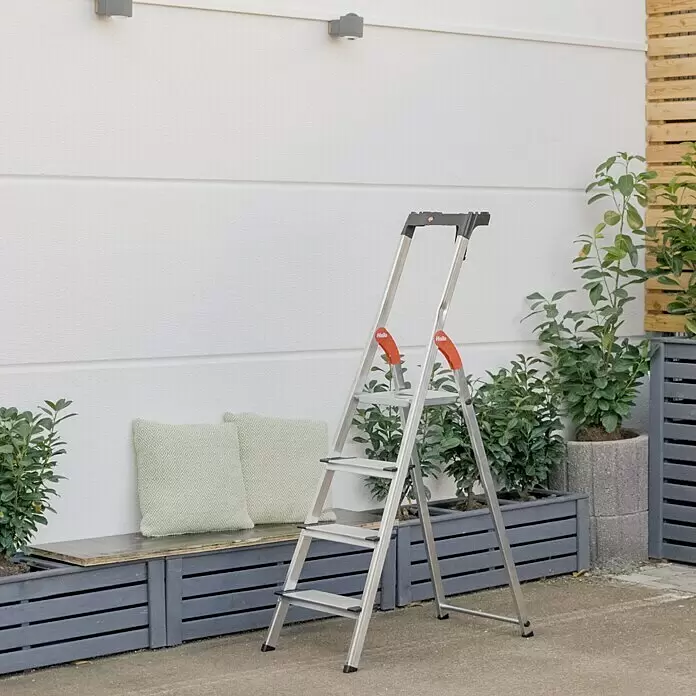 Hailo Stehleiter XXL - Anzahl Tritte: 4 Stk., Arbeitshöhe: 2,6 m, Belastbarkeit: 150 kg, Aluminium - Eine silberne 3-stufige Leiter mit orangen Akzenten steht im Freien.