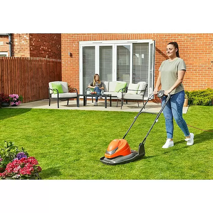 Flymo Elektro-Luftkissenmäher SimpliGlide 360 - Schnittbreite: 36 cm - Eine Frau schiebt einen orange-grauen Elektrorasenmäher über einen grünen Rasen.