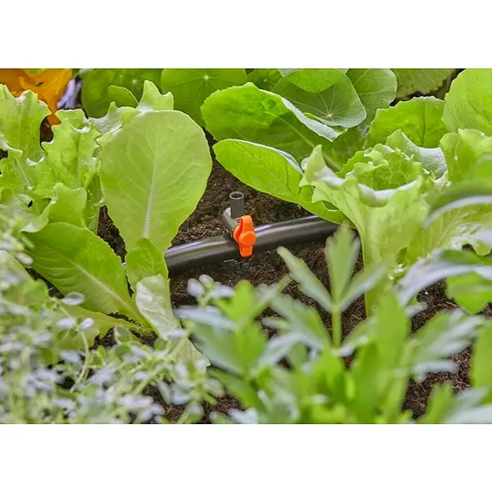 Gardena Micro-Drip Válvula de regulación - 3/16" x 4,6 mm, 4 ud. - Primer plano de un sistema de riego en medio de un jardín con lechugas, que permite un riego eficiente y preciso.