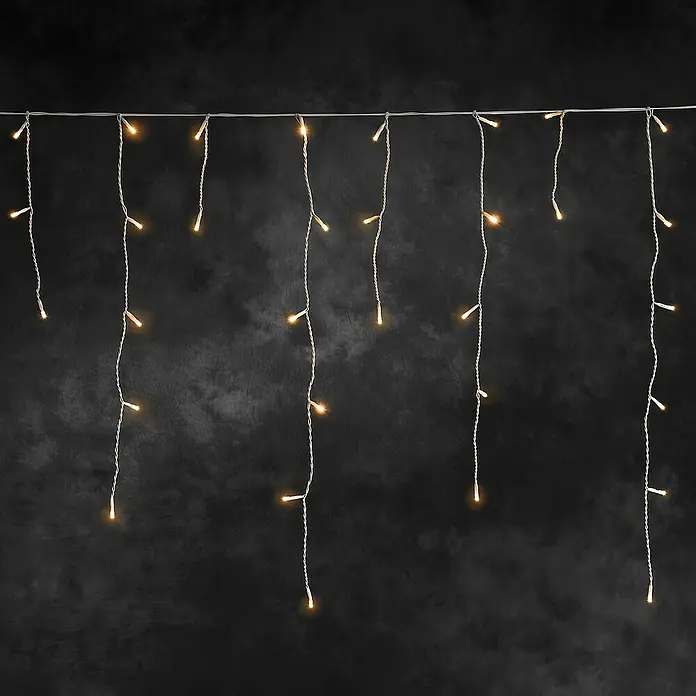 Konstsmide LED-Lichtervorhang - Außen, 6,37 m, Bernstein, 200 Stk., Akkubetrieben - Dekorative Lichterkette mit warmweißen LEDs an silberfarbenen Drähten vor einem dunklen Hintergrund.