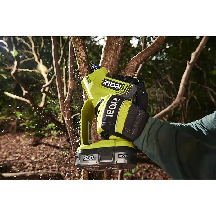 Ryobi ONE+ Akku-Astsäge RY18PSX10A-0 - 18 V, Li-Ionen, Ohne Akku, Schwertlänge: 10 cm - Nahaufnahme einer Ryobi Akku-Kettensäge beim Beschneiden eines Baumes, Späne fliegen. Werkzeug mit Handschuhen in Aktion.