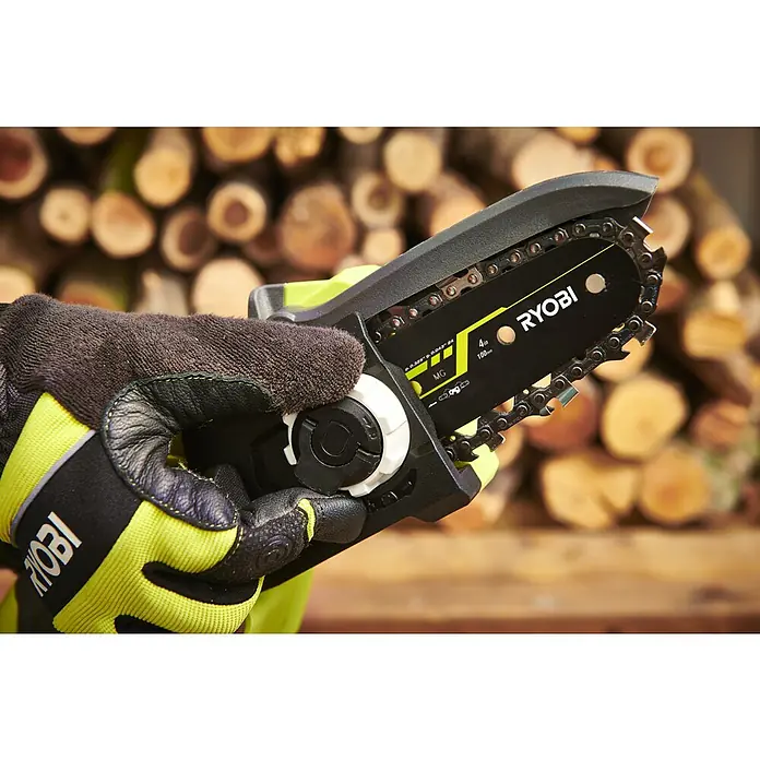 Ryobi ONE+ Akku-Astsäge RY18PSX10A-0 - 18 V, Li-Ionen, Ohne Akku, Schwertlänge: 10 cm - Nahaufnahme einer Ryobi Akku-Kettensäge, die in einer Hand gehalten wird, mit einem Stapel Holzscheite im Hintergrund.