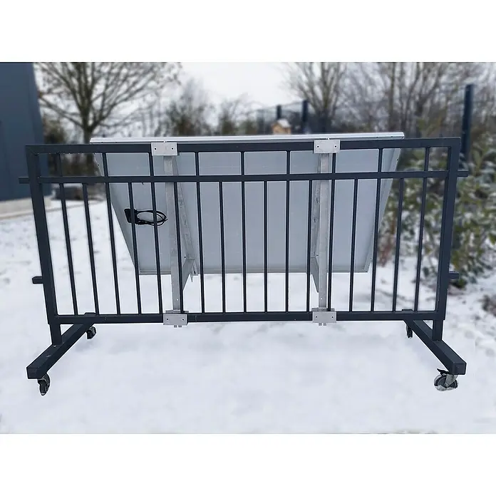 Technaxx BefestigungsbügelPassend für: Technaxx Balkonkraftwerk TX-212 - Hier ist ein Solarmodul, das mit Halterungen an einem schwarzen Geländer mit Rädern befestigt ist. Das Solarmodul ist hellgrau.
