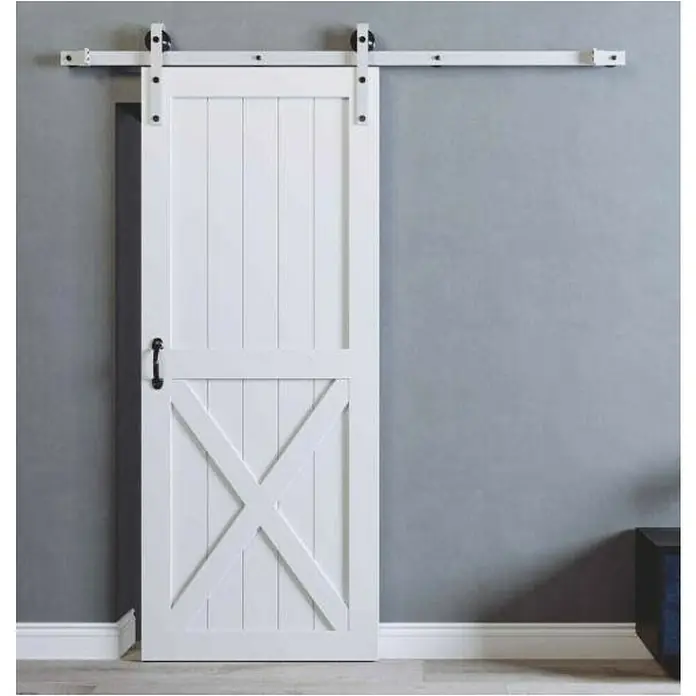 Puerta corredera de madera Avery - An x Al: 85 x 210 cm - Elegante puerta de granero blanca con diseño en forma de X y manija negra. La puerta cuelga de una robusta guía blanca con rodillos negros.