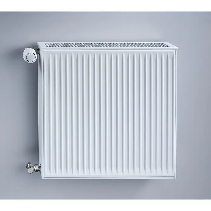 Austauschheizkörper - B x H: 1.600 x 550 mm, Wärmeleistung bei Vorlauftemperatur von 75 °C (D: 50): 3.568 W, Typ Heizkörper: 33 - Nahaufnahme eines weißen Heizkörpers mit Thermostat an einer grauen Wand. Das Heizgerät ist quadratisch und besteht aus gerippten Paneelen.