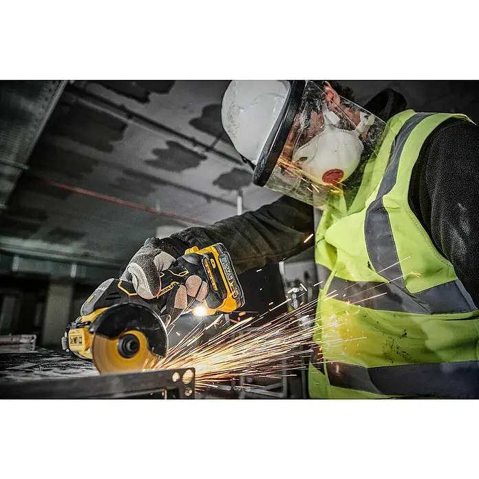 DeWalt XR 18V Akku-Winkelschleifer DCS438N-XJ - 18 V, Ohne Akku - Funkensprühend bearbeitet ein Arbeiter mit einer DeWalt Akku-Flex ein Metallstück, wobei er Schutzkleidung trägt.
