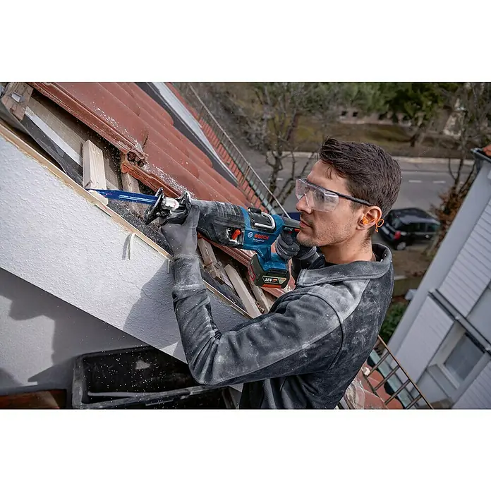 Bosch Professional AMPShare 18V Akku-Säbelsäge GSA 18V-28 - 18 V, Li-Ionen, Ohne Akku, Koffer - Ein Handwerker benutzt eine Bosch Säbelsäge, um Holz auf einem Dach zu schneiden, während er eine Schutzbrille und Ohrenschützer trägt.