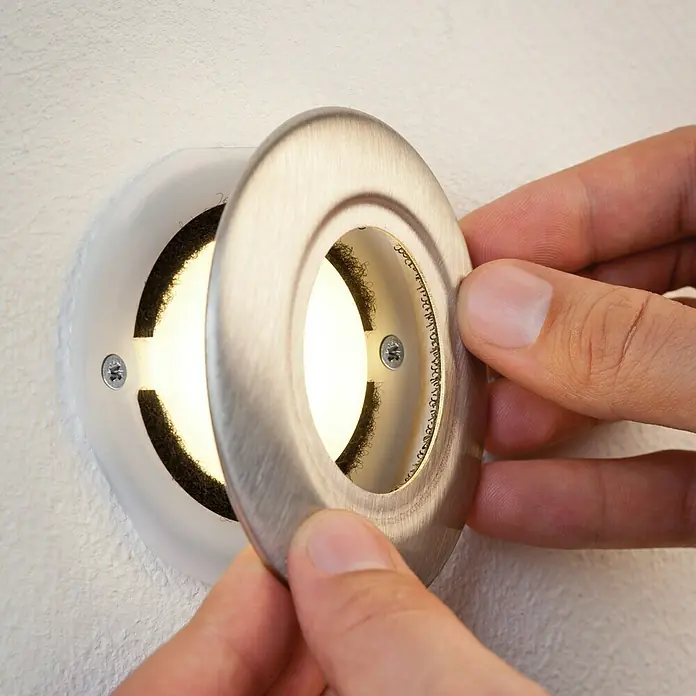 Paulmann Special Line LED-Einbauleuchten-Abdeckung - Edelstahl, Durchmesser: 86 mm, IP65 - Nahaufnahme einer Person, die eine silberne LED-Einbauleuchte an einer Wand befestigt.