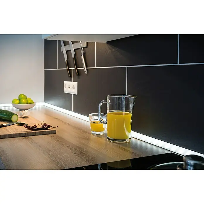 Paulmann Delta Profil - 2 m, Kunststoff - Nahaufnahme eines Küchentisches mit einem Krug und einem Glas Saft, der von LED-Leuchten unter dem Schrank beleuchtet wird.