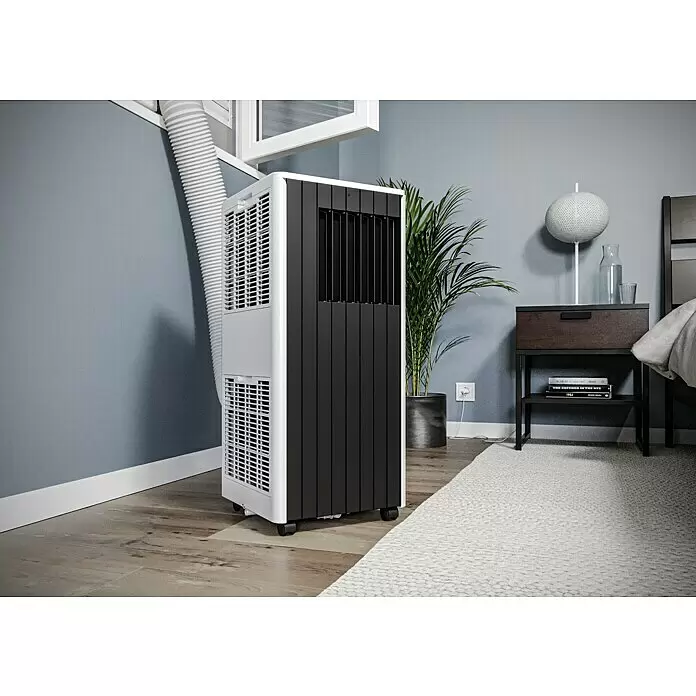 Voltomat Aire acondicionado portátil WiFi Khione - 2.600 W, Tamaño de la estancia: 26 m², Negro - Aire acondicionado portátil blanco y negro con manguera de escape conectada a una ventana, en el suelo de madera de un dormitorio.
