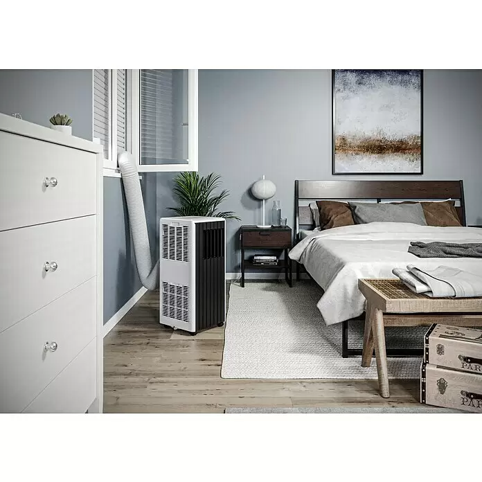Voltomat Aire acondicionado portátil WiFi Khione - 2.600 W, Tamaño de la estancia: 26 m², Negro - Aire acondicionado portátil blanco y negro en un dormitorio moderno, con una manguera flexible que va a una ventana abierta para ventilación.