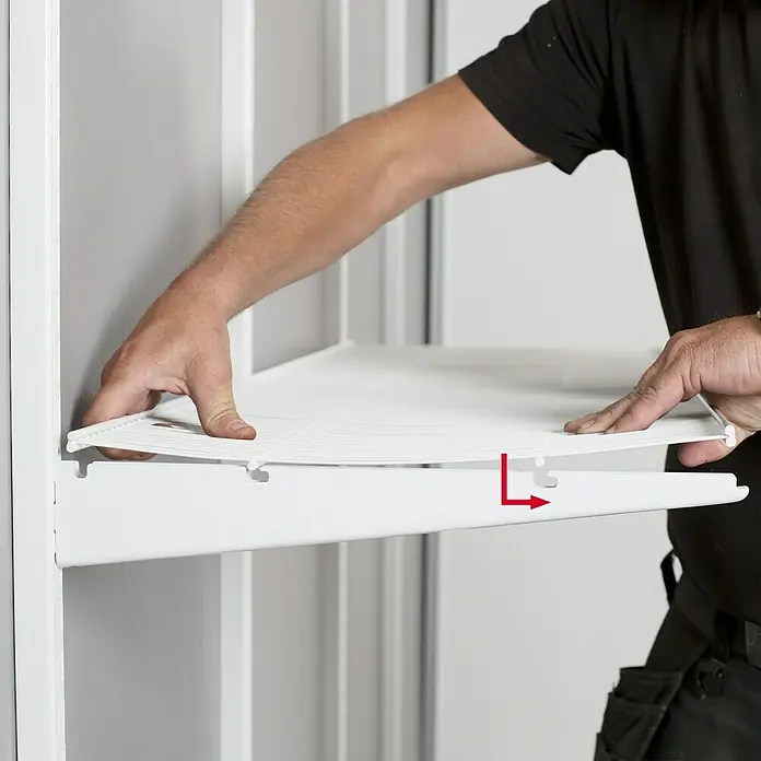 Lundbergs Drahtbodenträger - L x B x H: 494 x 12 x 78 mm, Weiß, Geeignet für: Gitterfachböden - Nahaufnahme einer Person, die eine weiße Regalböden in ein Schranksystem einbaut.