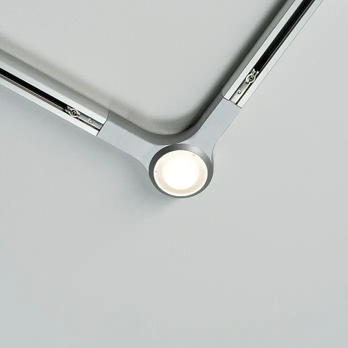 Paulmann URail L-Verbinder LED - L x B x H: 14,1 x 14,1 x 2,7 cm, Chrom matt - Detailaufnahme einer modernen, silbernen Deckenleuchte mit einem runden LED-Spot, der helles Licht ausstrahlt. Das minimalistische Design fügt sich nahtlos ein.