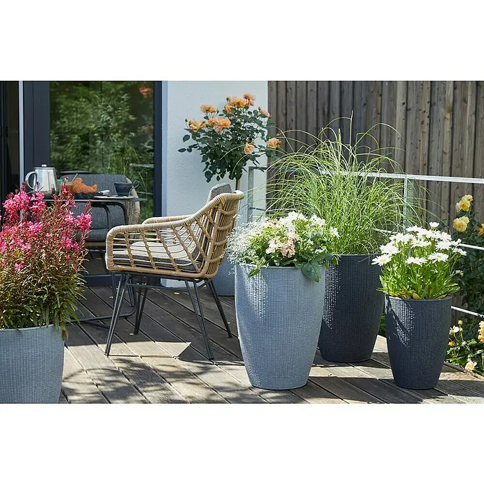 Scheurich Barceo Pflanzsäule rund - Außenmaß (Ø x H): 29 x 40 cm, Kunststoff, Granitschwarz - Ein Arrangement aus Pflanzgefäßen in verschiedenen Farben und Größen mit üppiger Bepflanzung auf einer Holzterrasse.