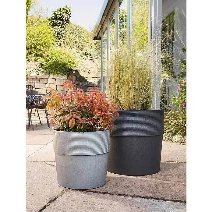 Scheurich Groove Pflanztopf + - Außenmaß (Ø x H): 28,5 x 26,2 cm, Kunststoff, Carbonschwarz - Zwei texturierte Pflanztöpfe, hellgrau und dunkelgrau, mit Pflanzen auf einer Außenterrasse.