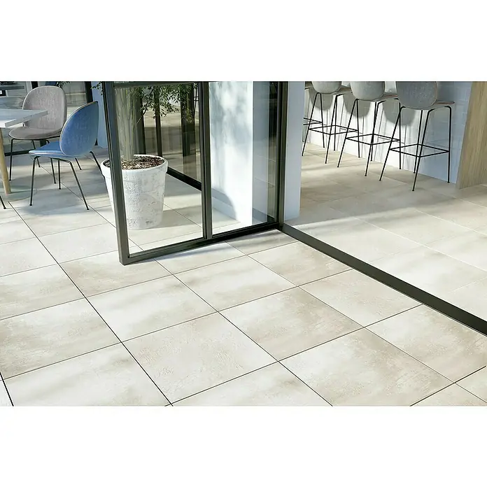 Cersanit Terrassenfliese Beton White - 59,3 x 59,3 x 2 cm, Weiß, Matt - Helle Bodenfliesen mit quadratischem Muster und dunklen Fugen, ergänzt durch eine moderne Glastür mit schwarzem Rahmen.