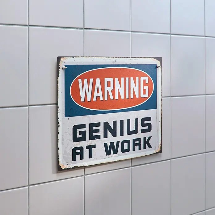 Tesa Tornillo adhesivo ajustable - Rectangular, Carga soportada: 3 kg, 2 ud. - Letrero de advertencia "Genio trabajando" en una pared de azulejos blancos, mostrando humor y decoración reflexiva.