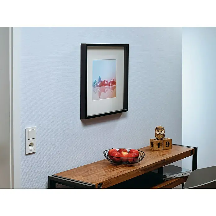 Tesa Clavo adhesivo ajustable - Blanco, Carga soportada: 1 kg, 2 ud. - La foto muestra una habitación moderna con una elegante estantería de madera y una obra de arte enmarcada en la pared.