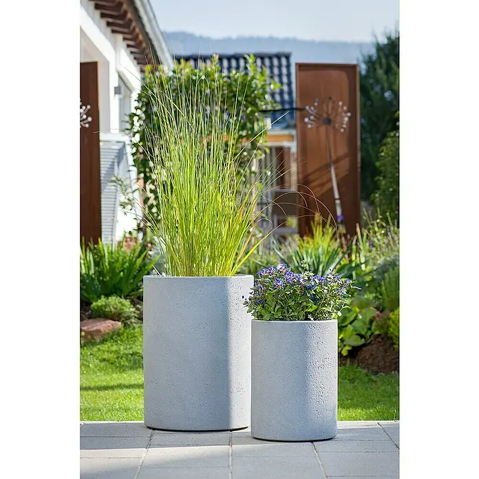 Scheurich Riva Pflanzsäule rundAußenmaß (Ø x H): 38,5 x 53,4 cm, Kunststoff, Betongrau - Zwei zylindrische Pflanzgefäße aus Beton mit grünen und blauen Pflanzen, die eine moderne Gartengestaltung zeigen.