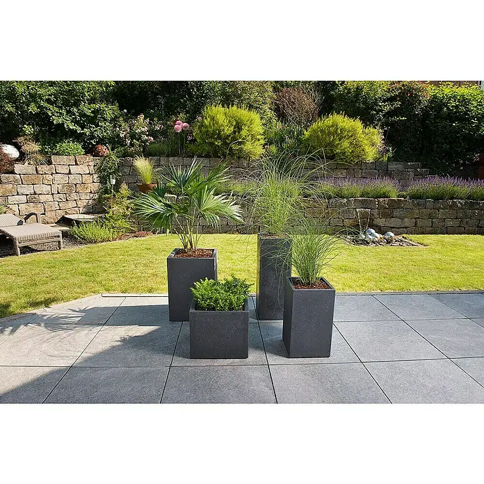 Scheurich Pflanzsäule eckig C-Cube - Außenmaß (L x B x H): 26 x 26 x 69,8 cm, Kunststoff, Schwarz - Vier moderne Pflanzgefäße in verschiedenen Größen mit grünen Pflanzen auf einer Terrasse mit Garten im Hintergrund.