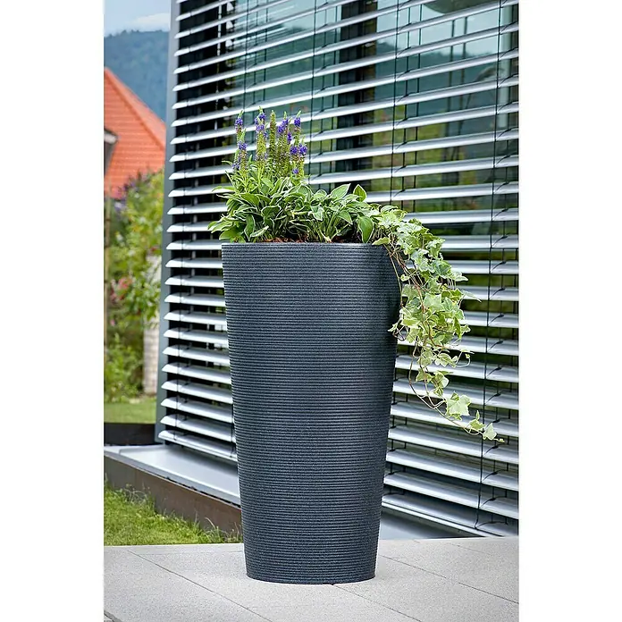 Scheurich Pflanzsäule rund Coneo - Außenmaß (Ø x H): 28,5 x 56,2 cm, Kunststoff, Granitschwarz - Ein grauer Pflanzkübel aus Kunststoff mit horizontalen Rillen und üppiger Bepflanzung im Außenbereich.