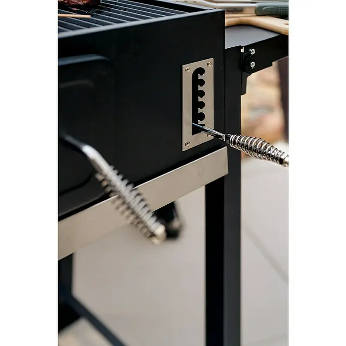Kingstone KMS Holzkohlegrill Black Angus XXL - Grillfläche (B x T): 70 x 43,5 cm, Schwarz - Detailaufnahme eines schwarzen Grills mit einem Hebel zur Höhenverstellung des Grillrosts. Der Hebel ist aus Metall und hat einen spiralförmigen Griff.
