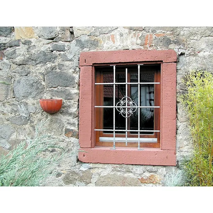 Stabilit Fenstergitter - B x H: 168 x 84 cm, Montage Fenstergitter: Fensterlaibungsmontage - Fenster mit Ziergitter in einer Steinmauer. Das Gitter schützt und schmückt, während die Mauer rustikalen Charme versprüht.