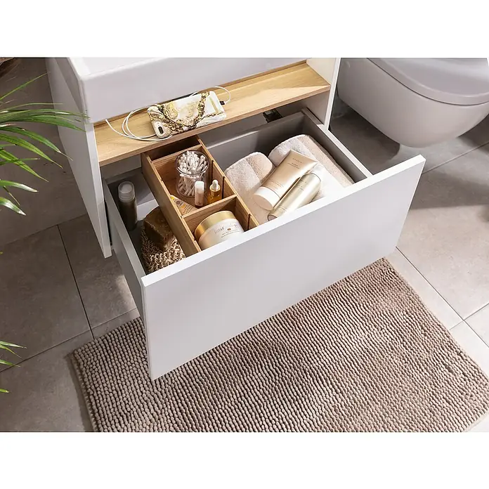 Camargue Nature Badmöbel-Set NA61M - Gesamtbreite Badmöbel: 60 cm, Weiß, Matt - Ein Badezimmerwaschtisch mit einer offenen Schublade, in der Pflegeprodukte und ein Badteppich zu sehen sind.