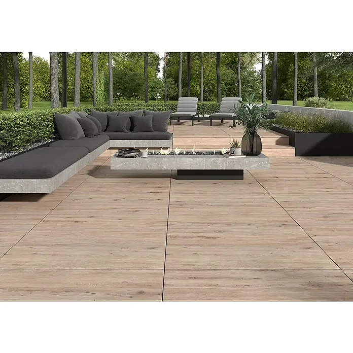 Terrassenfliese Garden Coldbrown 2.0 - 39,7 x 119,7 x 2 cm, Grau/Braun, Matt - Terrassenbild mit hellen Holzdielen, grauer Sitzecke und modernem Tisch mit integriertem Kamin für gemütliche Stunden im Freien.