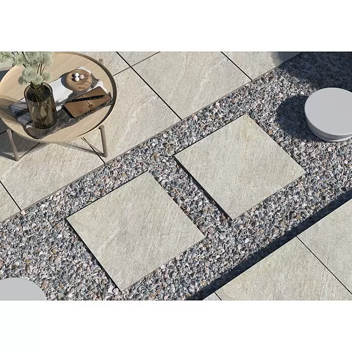 Terrassenfliese Piazza 2.0 - 59,7 x 59,7 x 2 cm, Sabbia, Matt - Helle, quadratische Terrassenplatten bilden einen Weg, getrennt durch ein Band aus mehrfarbigem Kies, mit Beistelltisch und Hocker.