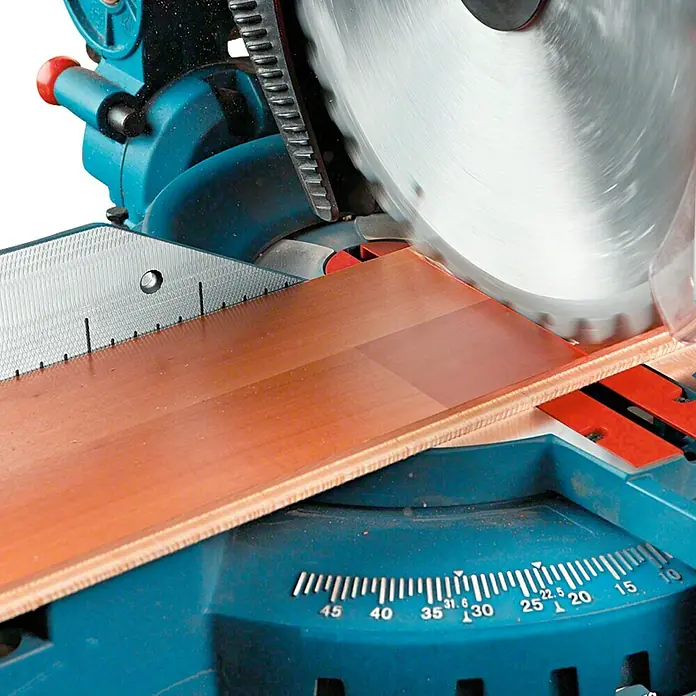 Bosch Professional Sierra ingletadora GTM 12 JL - Diámetro hoja de sierra: 305 mm - Una sierra ingletadora cortando una pieza de madera. La sierra es azul y negra y la pieza de madera es marrón claro.