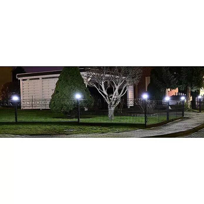 Hadra Pfostenkappe Solar - 24 x 20 cm, Kunststoff - Helle weiße LED-Leuchten beleuchten einen dunklen Metallzaun und Gartenweg bei Nacht.