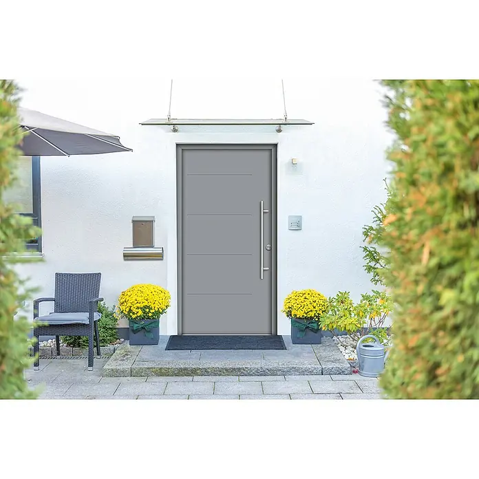 Splendoor Haustür Thermodoor PLUS SPL - 100 x 210 cm, DIN Anschlag: Rechts, Verkehrsgrau - Graue Haustür mit senkrechtem Griff und Oberlicht, flankiert von üppigen gelben Blumenarrangements, die einen einladenden Eingangsbereich schaffen.