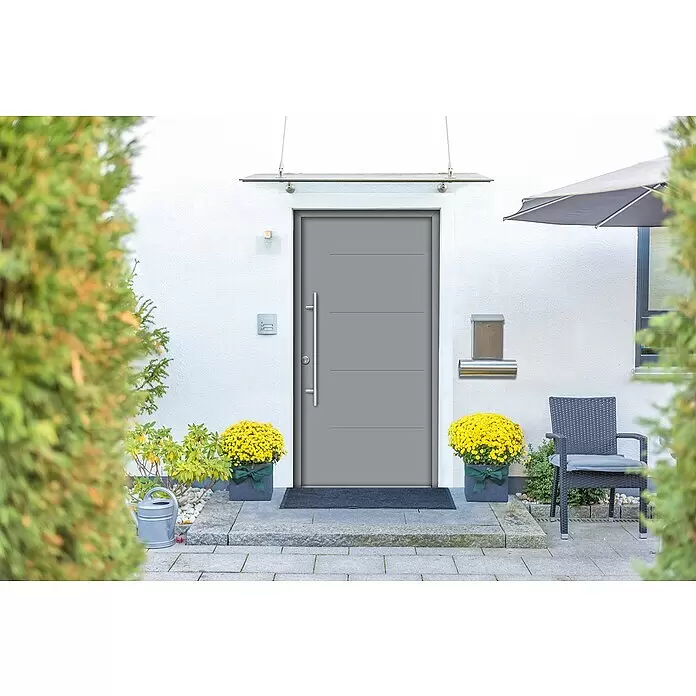 Splendoor Haustür Thermodoor PLUS SPL - 100 x 210 cm, DIN Anschlag: Links, Verkehrsgrau - Moderne graue Haustür mit langem silbernem Griff, eingebaut in einen Hauseingang mit gelben Blumen und Briefkasten.