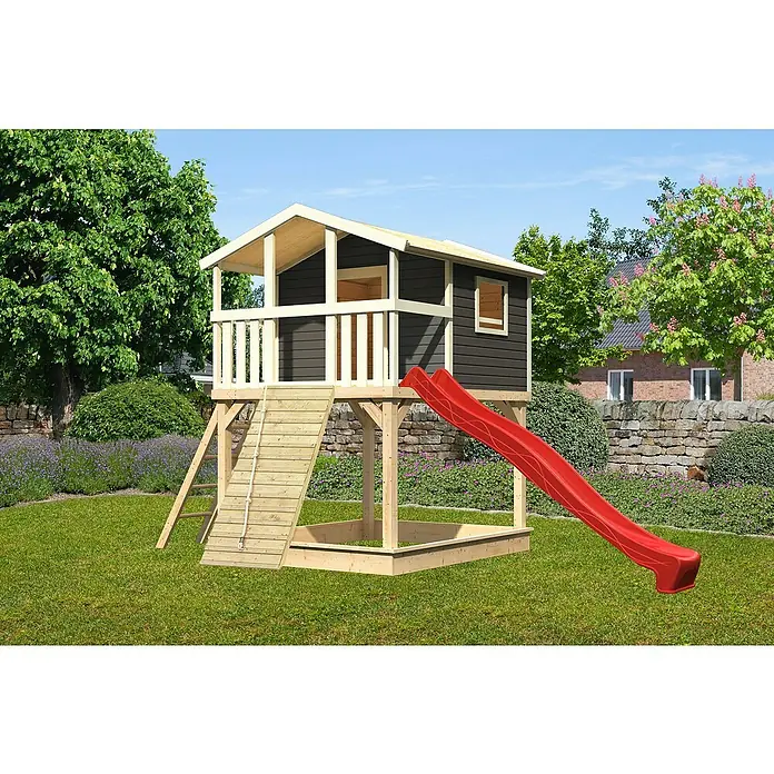 Karibu Spielhaus Benjamin Set 18 - L x B x H: 244 cm x 198 mm x 309 cm, Holz, Terragrau - Das Bild zeigt ein hölzernes Spielhaus mit Rutsche und Sandkasten in einem Garten. Das Spielhaus ist dunkelgrau mit weißen Akzenten.