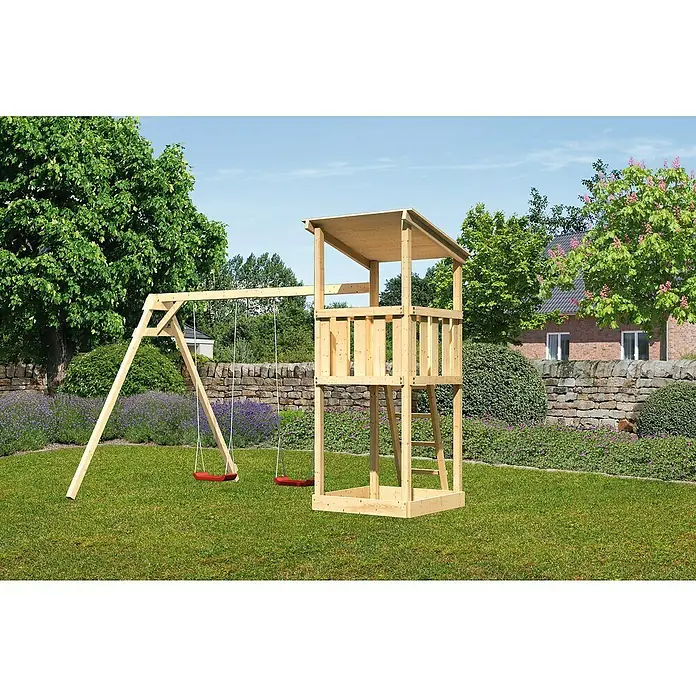 Karibu Kinderspielturm Anna Set 4 - L x B x H: 264 x 347 x 270 cm, Natur - Ein hölzerner Spielturm mit Schaukel steht auf einer grünen Wiese, umgeben von Bäumen und Sträuchern, ideal für den Garten.