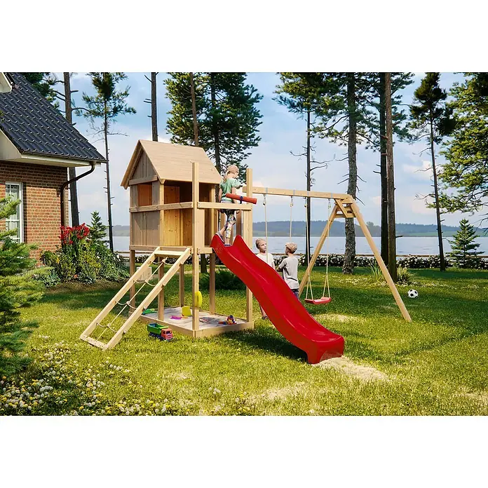 Karibu Kinderspielturm Frieda Set 32 - L x B x H: 264 x 347 x 291 cm, Natur - Ein hölzerner Spielturm mit Rutsche, Schaukel und Sandkasten steht auf einer grünen Wiese, perfekt für stundenlangen Spielspaß im Freien.