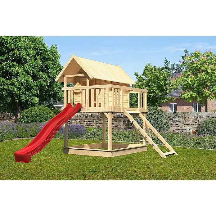 Karibu Kinderspielturm Fidel Set 12 - L x B x H: 243 x 198 x 329,5 cm, Natur/Rot - Ein hölzernes Spielhaus mit Rutsche und Sandkasten im Garten. Das Haus steht auf Stelzen und hat eine Leiter.
