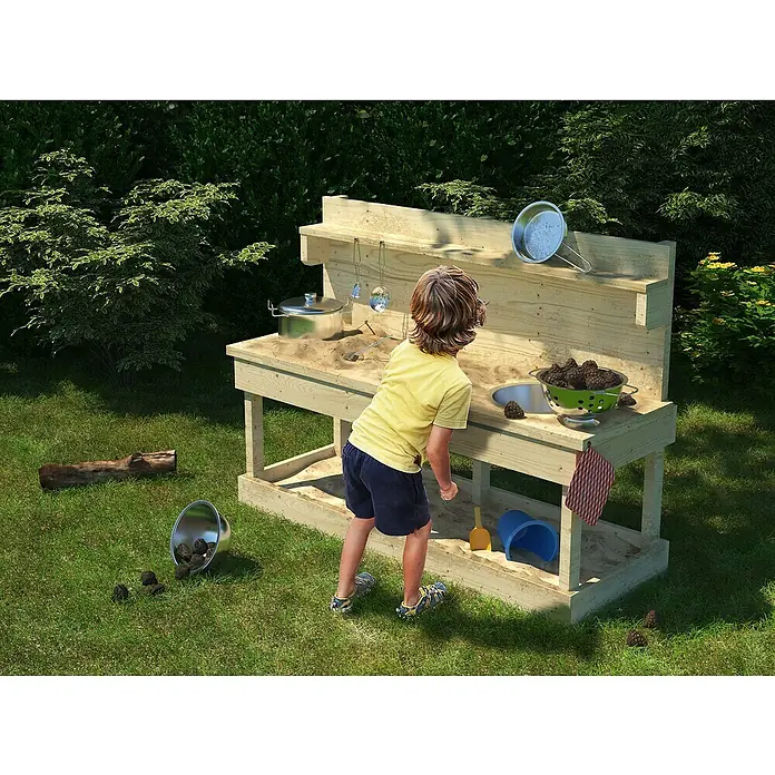 Karibu Matschküche Sandy - 44 x 119,5 x 79 cm, Holz, Natur - Ein Kind spielt an einer Outdoor-Spielküche aus Holz mit Zubehör wie Töpfen und Schüsseln im Garten.