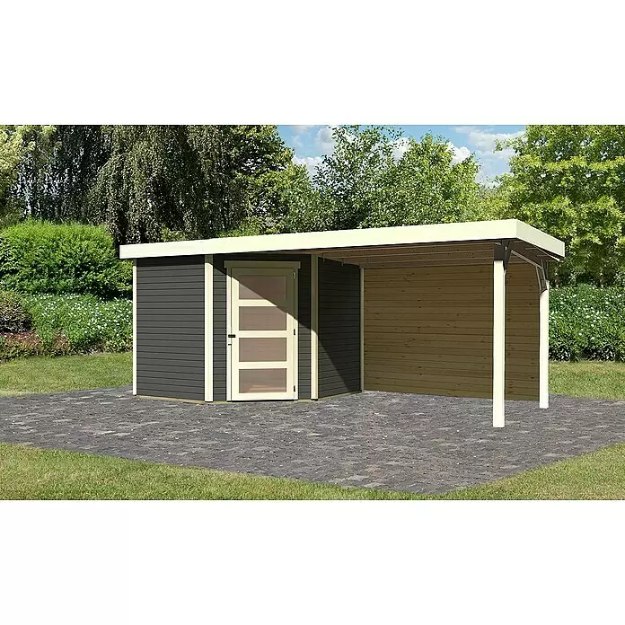 Karibu Gartenhaus Schwandorf 5 - Außenmaß inkl. Dachüberstand (B x T): 529,5 x 262 cm, Holz, Terragrau, Mit Seitendach und Rückwand - Dunkelgraues Holzgartenhaus mit heller Tür und integriertem Carport aus Naturholz, auf Pflastersteinen im Garten.