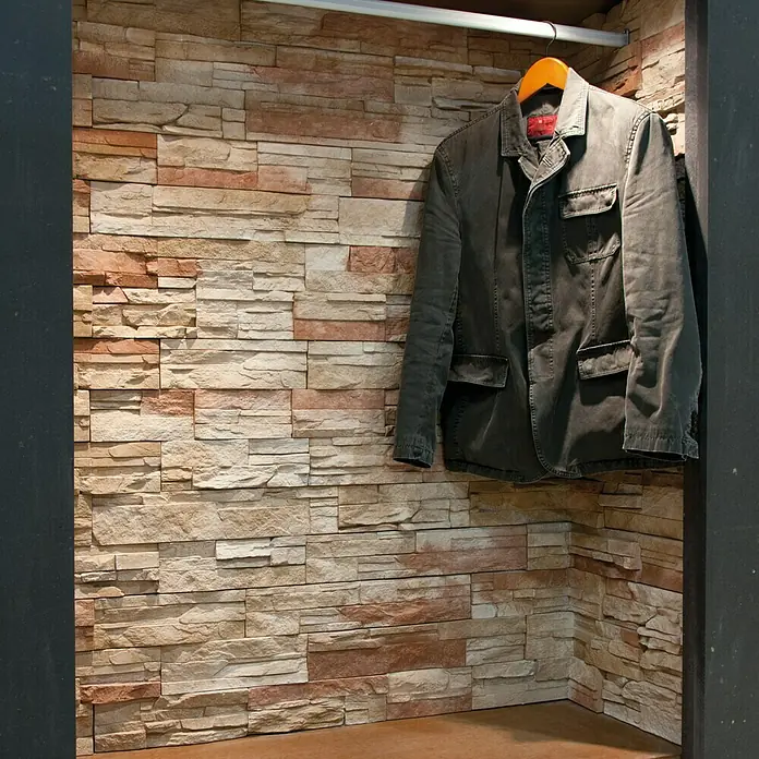 Esquina interior Petra Ágata - 30 x 30 x 11 cm - Una chaqueta verde oliva cuelga de una percha de madera en un armario rústico con pared de piedra. Prenda de abrigo elegante.