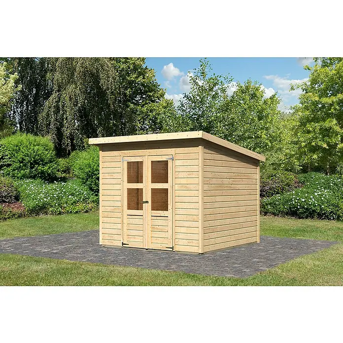 Karibu Gartenhaus Merseburg 6 - Außenmaß inkl. Dachüberstand (B x T): 265 x 265 cm, Holz, Natur, Ohne Seitendach - Hölzernes Gartenhaus mit Doppeltür und Flachdach vor grünem Hintergrund. Das Haus steht auf einem dunklen Pflaster.