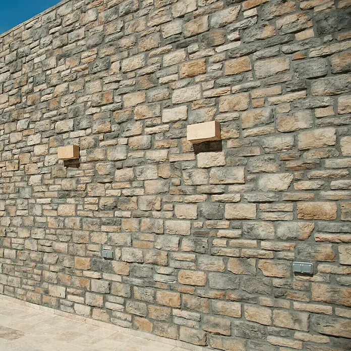 Revestimiento de piedra Silleria Plomo - Gris, Cantidad total: 4 pzs. - Primer plano de una fachada con ladrillos decorativos y dos ladrillos que sobresalen, añadiendo un acento arquitectónico único.