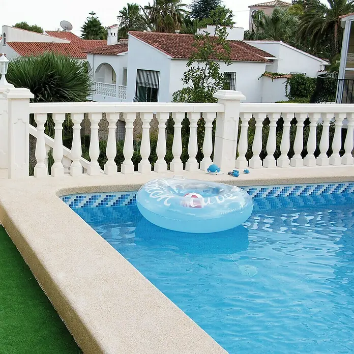 Balaustrada Italia 75 - 12 x 12 x 75 cm, Blanco, Hormigón - Flotador flotando en la piscina, rodeado de azulejos azules y vallas blancas, perfecto para la diversión veraniega y la relajación al aire libre.