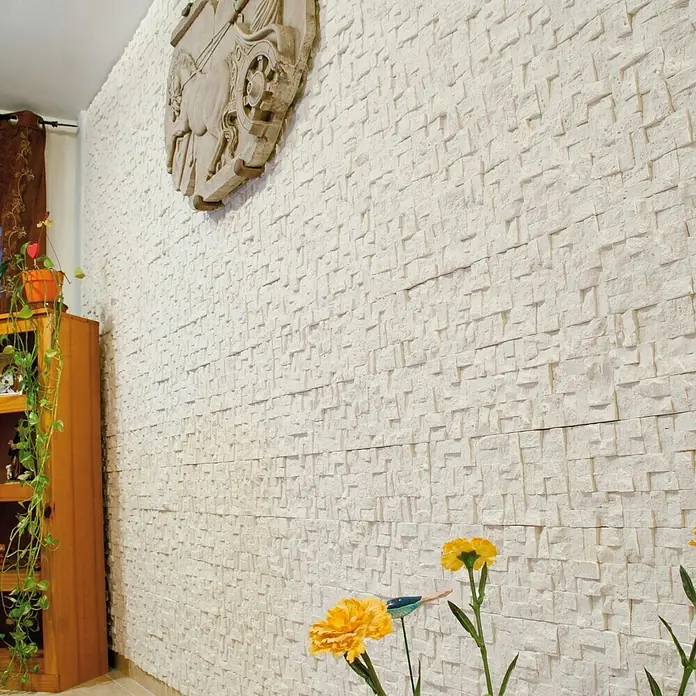 Revestimiento de piedra Trencadis Hueso - 30 x 15 x 2 cm - Primer plano de una pared con piedras decorativas y un relieve, creando un ambiente elegante y con estilo.