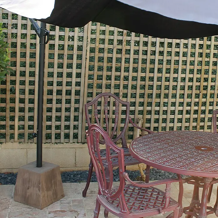 Base de parasol cuadrada - L x An: 26 x 18 cm - Una vista cercana de una mesa y sillas de jardín bajo una sombrilla, mostrando un ambiente exterior acogedor.