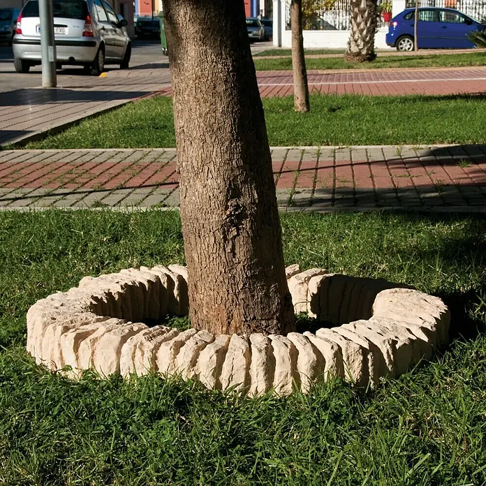 Paso para árboles Tostado - Piedra natural - Anillo de árbol segmentado de piedra en un césped, que rodea el tronco y ofrece protección.