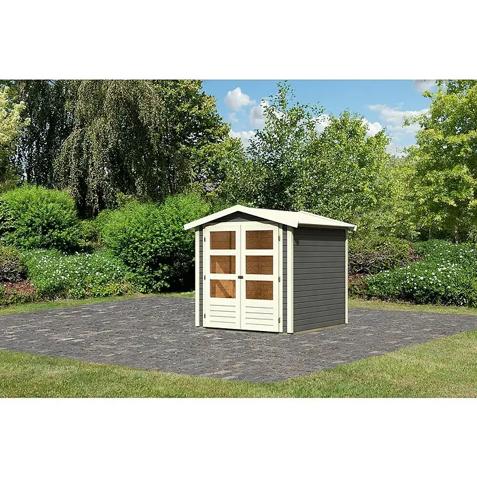 Karibu Gartenhaus Amberg 2 - Außenmaß inkl. Dachüberstand (B x T): 213 x 197 cm, Holz, Terragrau - Ein graues Gartenhaus mit Doppeltür und hellen Akzenten steht auf einem gepflasterten Bereich, umgeben von Grünpflanzen und Bäumen.