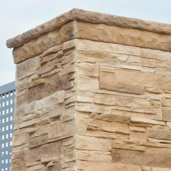 Moldura decorativa Petra Arena - 75 x 11 x 6 cm - Primer plano de un pilar esquinero hecho de mampostería beige, que muestra la robusta textura de la piedra y la paleta de colores naturales con una corona prominente.